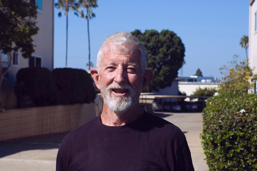 Headshot of an older smiling man with a beard