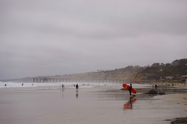 Beach with surfers in the background and gray skies above