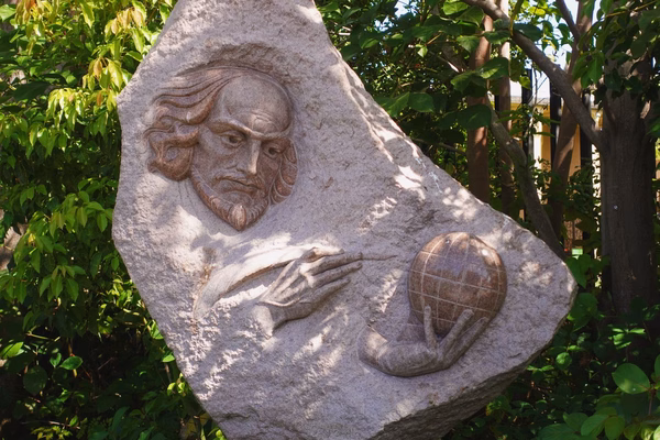 A concrete sculpture of Shakespeare holding a feather pen and a globe