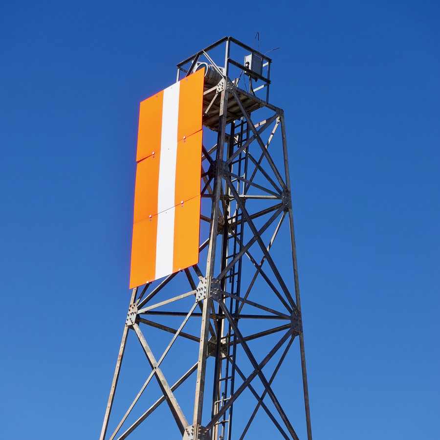Radio tower with a sign made of two orange stripes and one white stripe